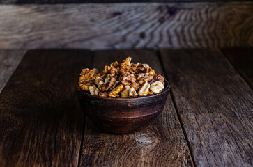 Peeled walnuts in an earthenware dish on a kitchen wooden table