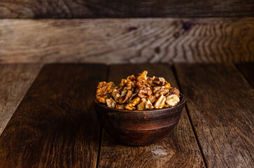 Peeled walnuts in an earthenware dish on a kitchen wooden table