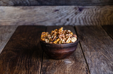 Peeled walnuts in an earthenware dish on a kitchen wooden table