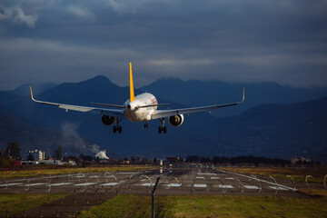 Fototapeta na wymiar Landing plane on cloudy sky background, rear view