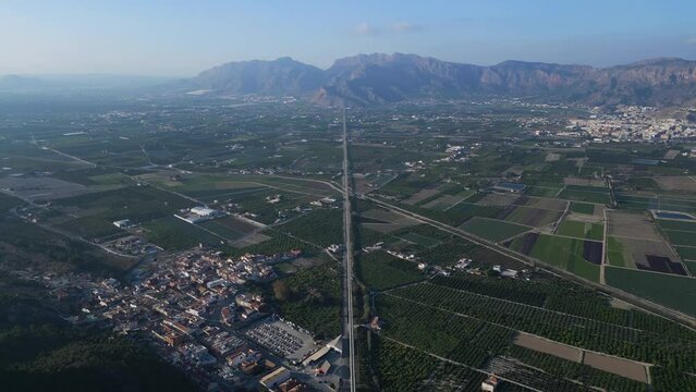 Aerial video of farmer's fields in Orihuela region with a rocky mountains in background.  Drone following big water tubes which part of the transfer of water from the Tagus River to the Segura River 