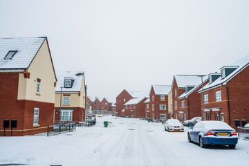 Road covered with snow and ice in winter near urban housing in southern England