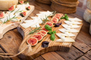 Delicious yummy cheese mix with figs on wooden board in restaurant. Tasting, degustation.