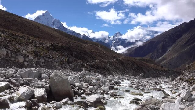 River flowing in valley with Ama Damblam and himalaya mountains 
blue sky and clouds in background, Nepal,2023
