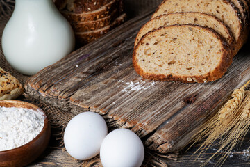 slices of rye bread, ears of wheat, eggs and a bowl of flour. Close-up.