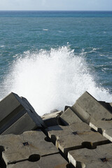 square breakwater structure made out of concrete on the coastline of Madeira, Portugal at Baija de...