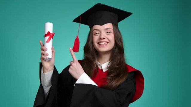 Close-up shot of a beautiful woman in black hat and gown holding her diploma. Portrait of a proud student achieving her goal. High quality 4k footage