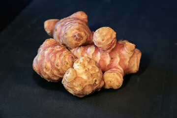 Unpeeled and raw Jerusalem artichokes or Topinambur on a table