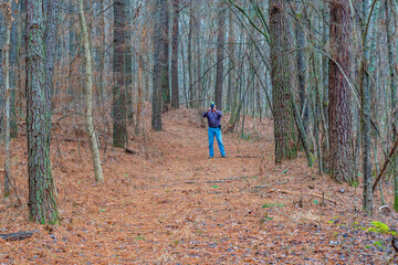 A man on a secluded dirt road in a pine forest taking cell phone pictures in Southern Tennessee.