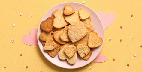 Plate of tasty heart-shaped cookies on yellow background. Valentine's Day celebration