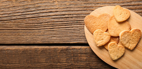 Board with sweet heart-shaped cookies on wooden background with space for text. Valentine's Day celebration