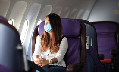 Traveling and Business during COVID-19 virus pandemic concept,woman wearing protective mask sitting near windows on airplane during flight