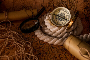 Fototapeta na wymiar Vintage compass, magnifier and rope on world map