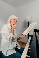 Older woman studying piano with music sheets on a grand piano