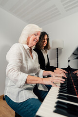 Piano teacher practicing piano lesson with senior female student