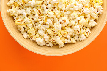 Bowl of delicious popcorn on color background, closeup