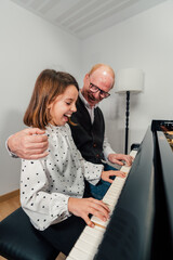 Senior piano student with her granddaughter playing the piano