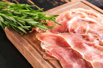 Wooden board with slices of tasty ham and rosemary, closeup