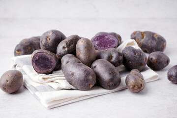 Heap of raw purple potatoes on light background, closeup