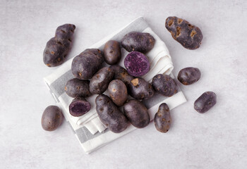 Heap of raw purple potatoes on light background