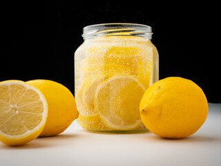 Lemon slices in glass jar filled up with refreshing soda. Black background, nobody.
