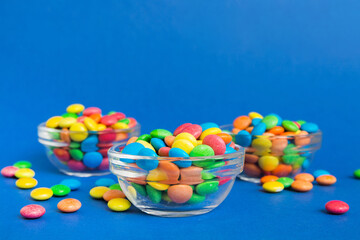 Multicolored candies in a bowl on a colored background. birthday and holiday concept. Top view with copy space