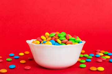 Multicolored candies in a bowl on a colored background. birthday and holiday concept. Top view with copy space