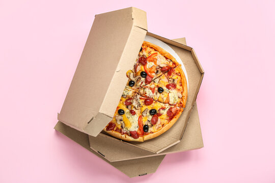 Stack of cardboard boxes with tasty pizza on pink background