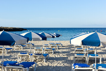 Sun loungers on a sandy beach with clear blue water at a holiday resort