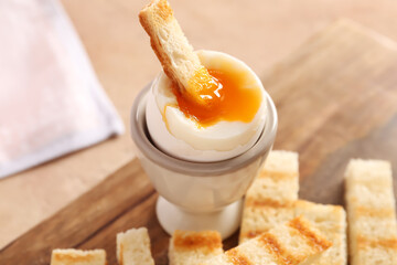 Holder with soft boiled egg and toasted bread on board