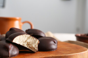 Wooden board with sweet chocolate bird's milk candies, closeup