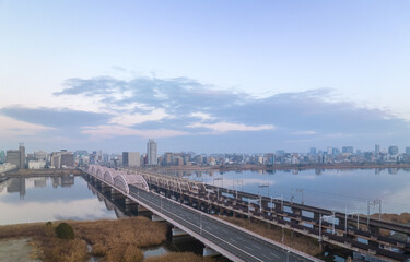Fototapeta na wymiar Empty vehicle and railroad bridges over river by city at dawn