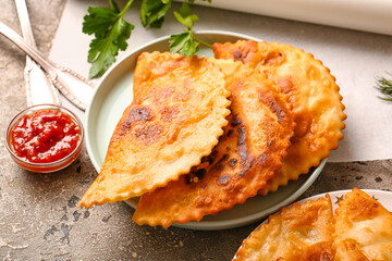 Plate with tasty chebureks and sauce on table