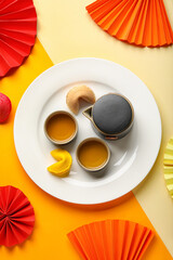 Plate with fortune cookies, teapot, cups and Chinese symbols on color background. New Year celebration
