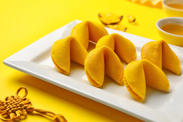 Plate with fortune cookies on yellow background, closeup. Chinese New Year celebration