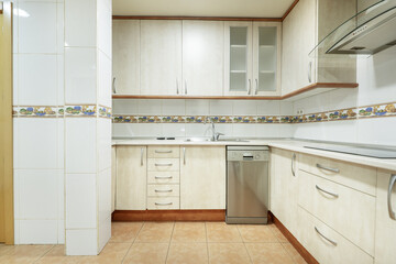 Frontal image of Kitchen with light wood furniture and cherry wood details with brown stoneware...