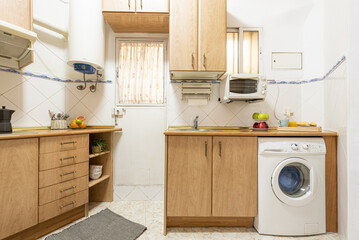 Conventional kitchen with light wood cabinets with white built-in appliances, white tile and small...
