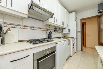 Old kitchen with white cabinets and appliances of all kinds and colors, cream countertops and matching tiles