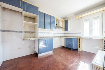 Fototapeta na wymiar Semi-furnished kitchen with granite countertops from which most of the appliances have been removed with red stoneware floors and aluminum windows with bars