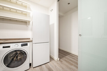 Corner of a kitchen with a tempered glass door, brownstone worktop and a white washing machine and...