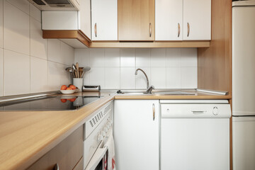 Corner of a kitchen with white cabinets combined with wood with matching worktop and wood and metal handles