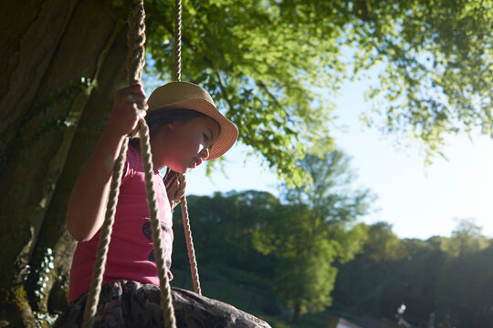 Side view of thoughtful girl swinging at playground