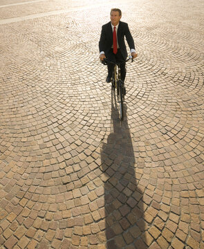 Elevated view of businessman riding bicycle thru piazza
