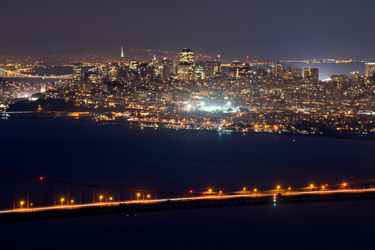 The city of San Francisco is illuminated at night above the span of the Golden Gate Bridge, CA.