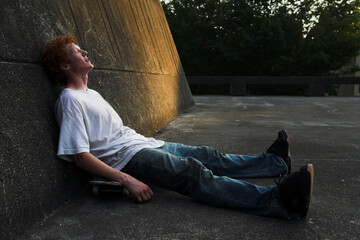 A teenager rests on his skateboard after a session on the angular concrete features by a high school.