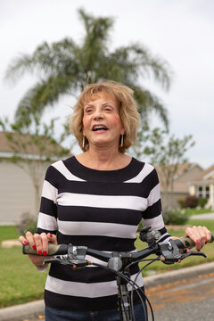 Mature Woman In Her Seventies Laughing Outside On Her Bike.