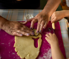 Hands of adult woman and a child cutting out cookies