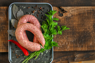  sausage rings close-up.Raw homemade sausage rings, fresh parsley, red chili peppers in a black...