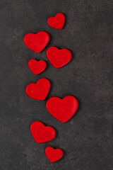 Obraz premium Cute festive Creamy jelly candies in the shape of a red heart with thematic inscription. Valentine's Day. Dark gray background. Copy space. Top view