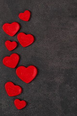 Creamy jelly candy in the shape of a red heart with thematic inscriptions. Valentine's Day. Dark gray background. Copy space